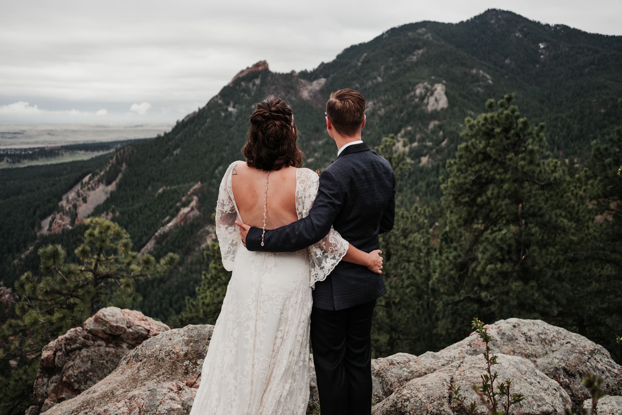 Hiking elopement photography, bride and groom hiking a mountain, Colorado wedding photographer, bride and groom looking at Boulder Flatirons