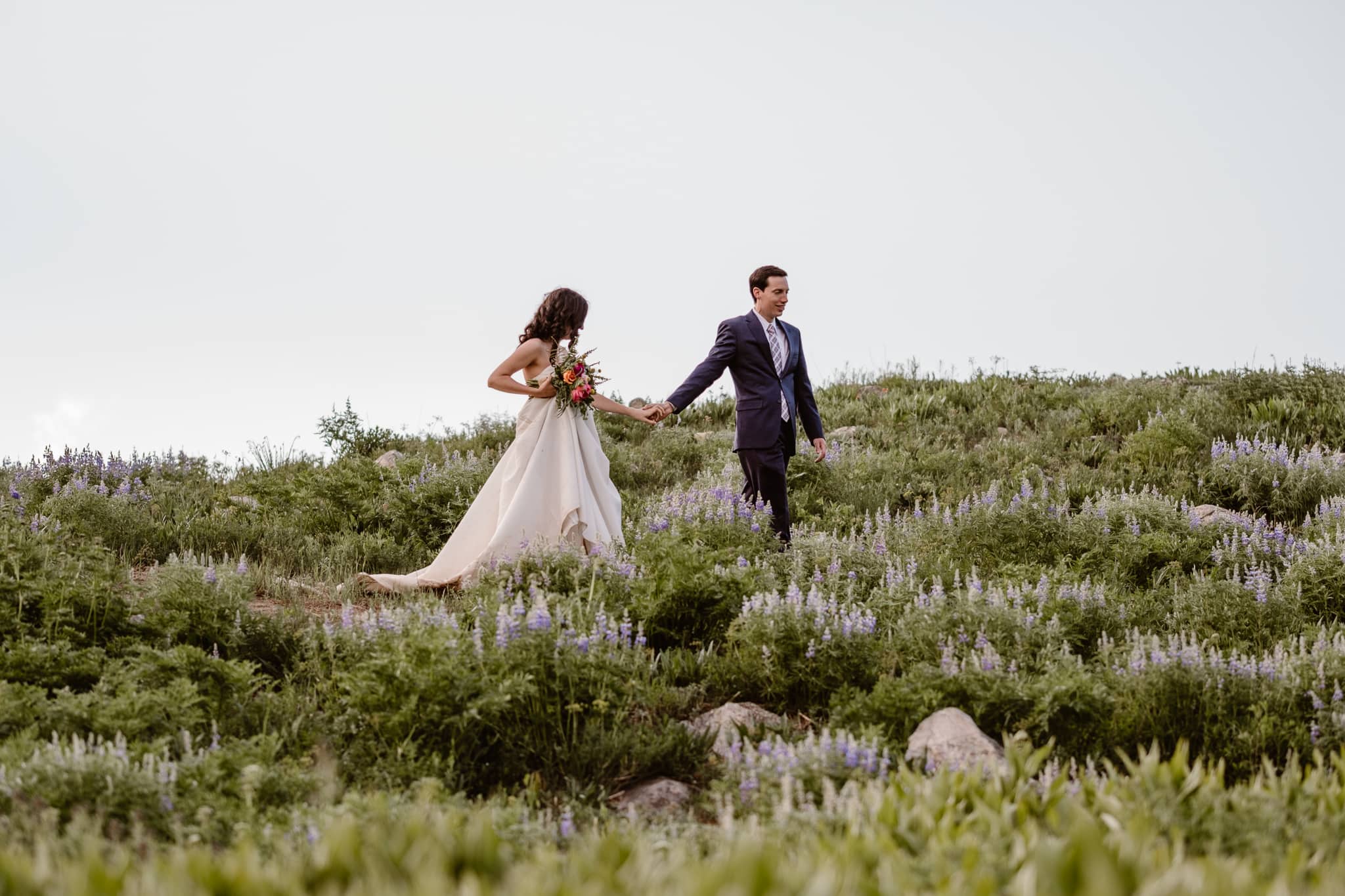 Crested Butte elopement photographer, Colorado adventure wedding photographer, bride and groom hiking through wildflowers, weekday elopement