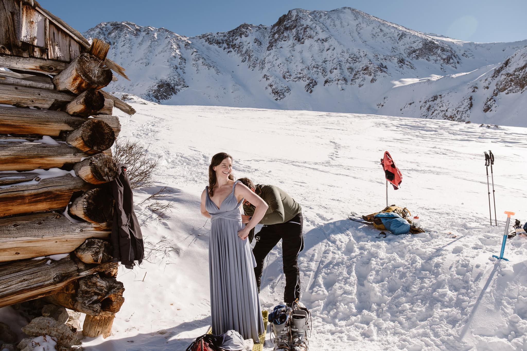 Bride and groom getting dressed by old mining cabin, Colorado winter elopement in the mountains, backcountry skiing elopement
