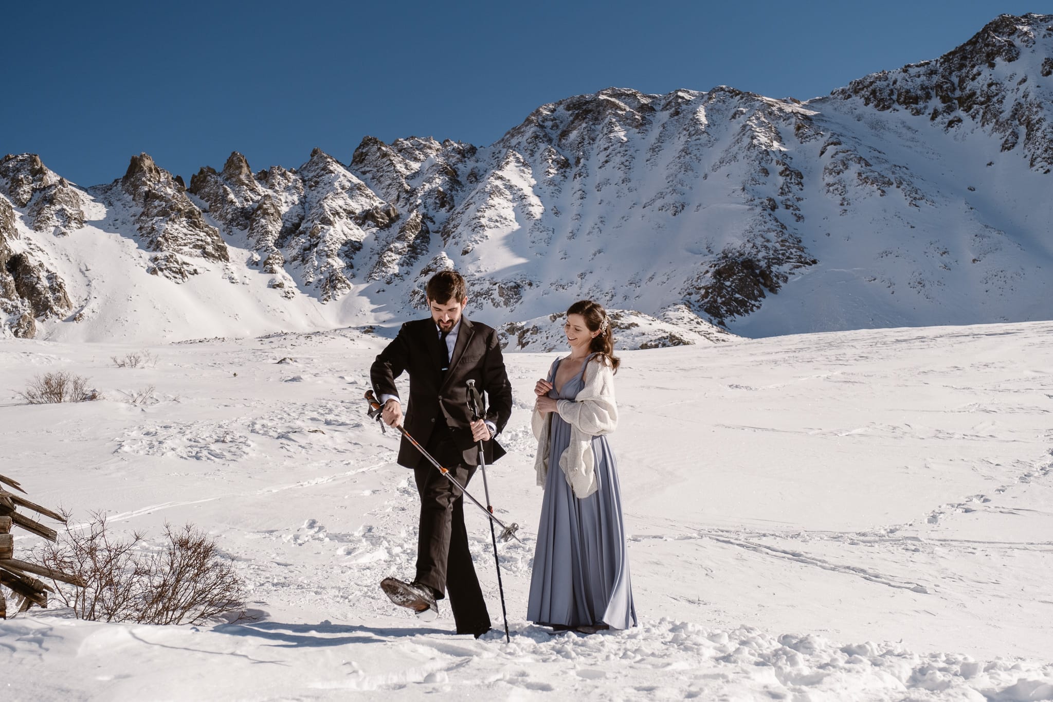 Bride and groom hiking with ski poles in snow, winter backcountry skiing elopement in Colorado mountains, adventure elopement photography
