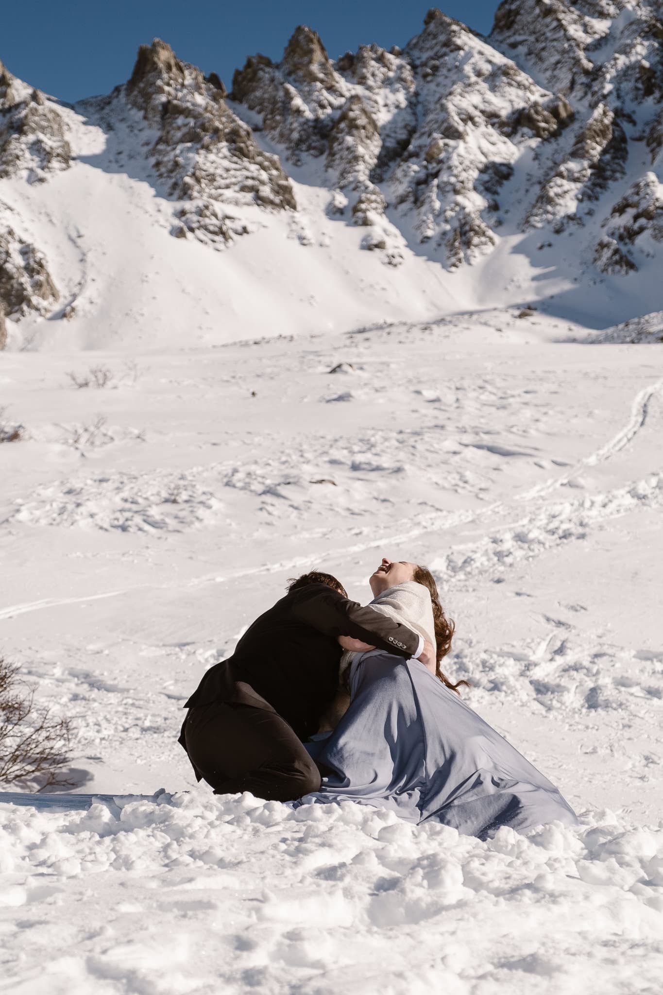 Bride and groom falling over in snow during first kiss, winter mountain elopement, Colorado snow elopement, winter wedding