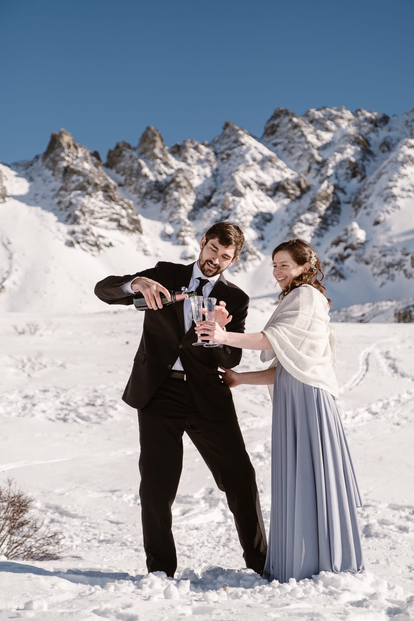 Bride and groom popping champagne bottle, winter mountain elopement, Colorado ski wedding, backcountry skiing elopement