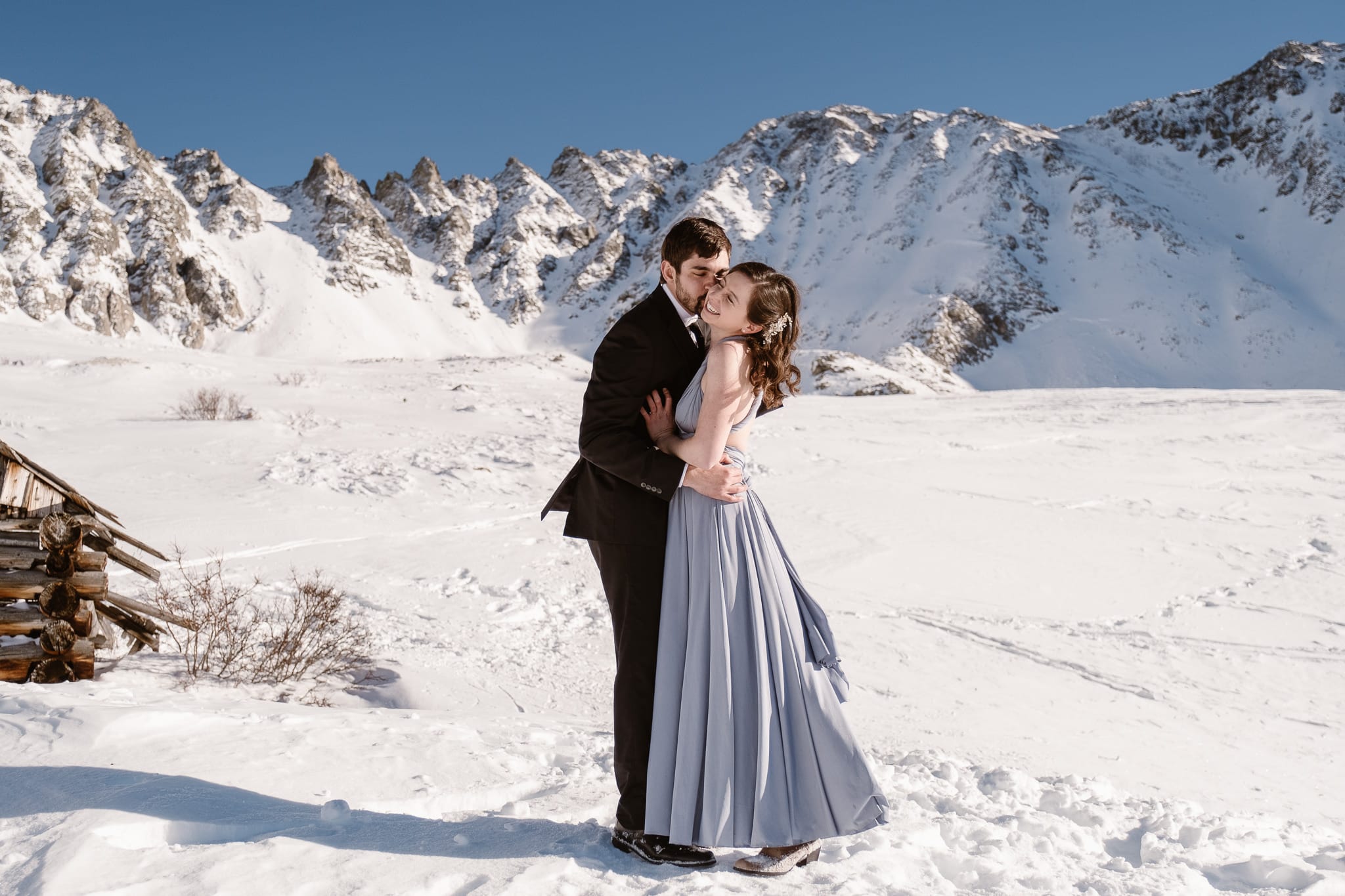 Backcountry skiing elopement in the snow-covered mountains of Colorado, bride wearing light blue wedding dress with open back