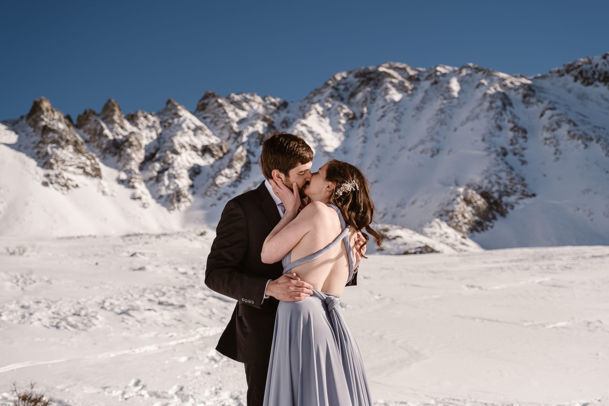 Backcountry skiing elopement in the snow-covered mountains of Colorado, bride wearing light blue wedding dress with open back