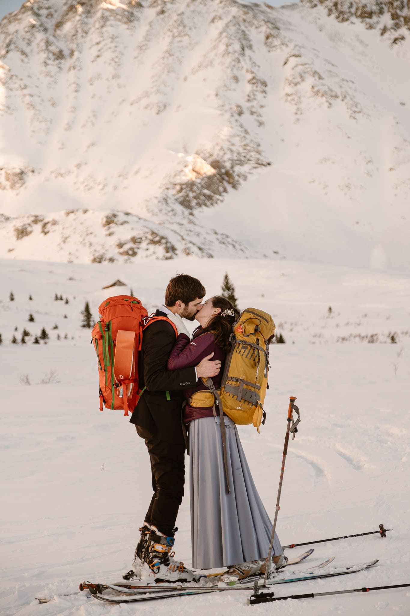 Bride and groom wearing backpacks, winter skiing elopement in Colorado mountains, backcountry skiing wedding