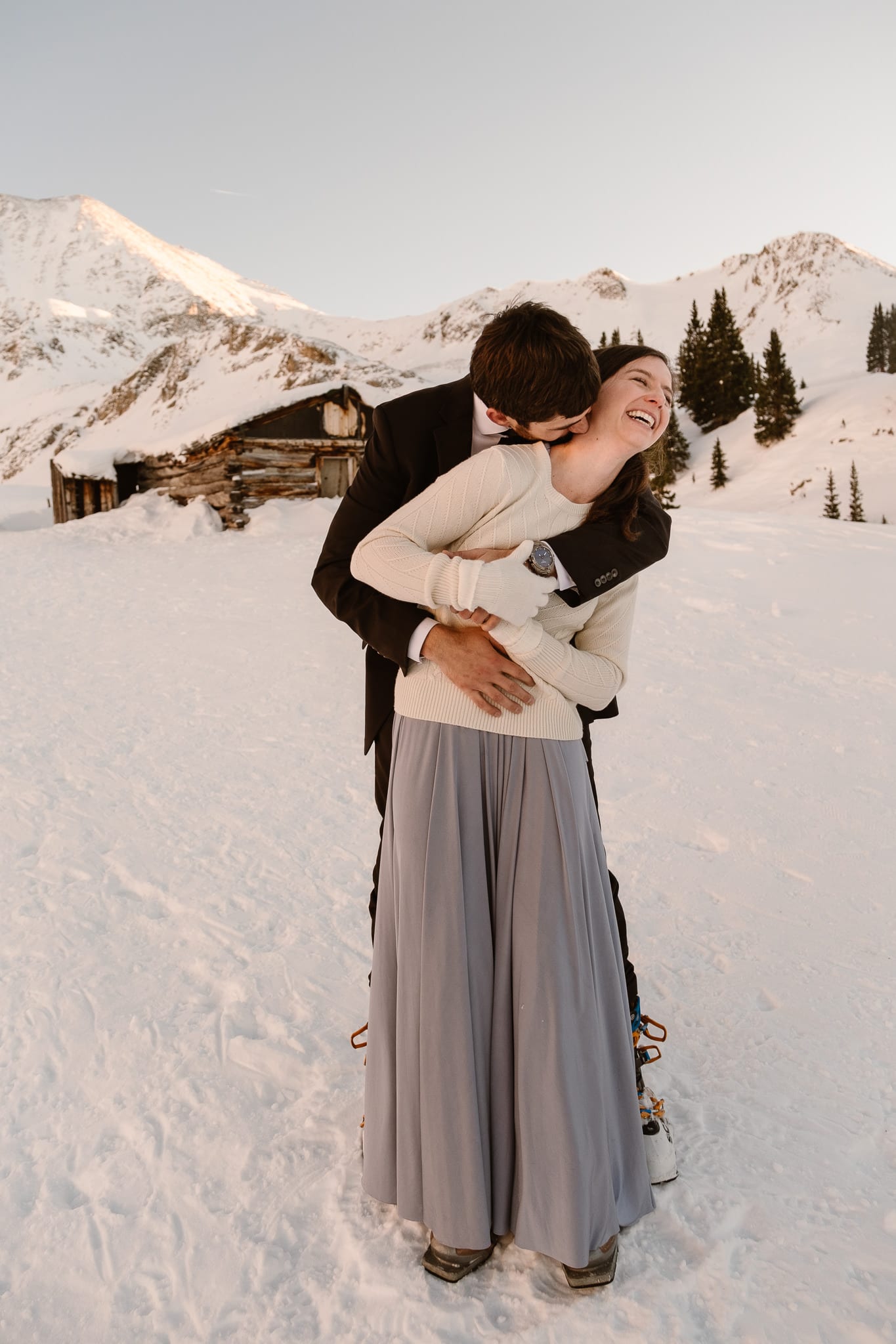 Bride and groom snuggle up close to stay warm at winter wedding, backcountry skiing elopement in Colorado, Colorado wedding photographer