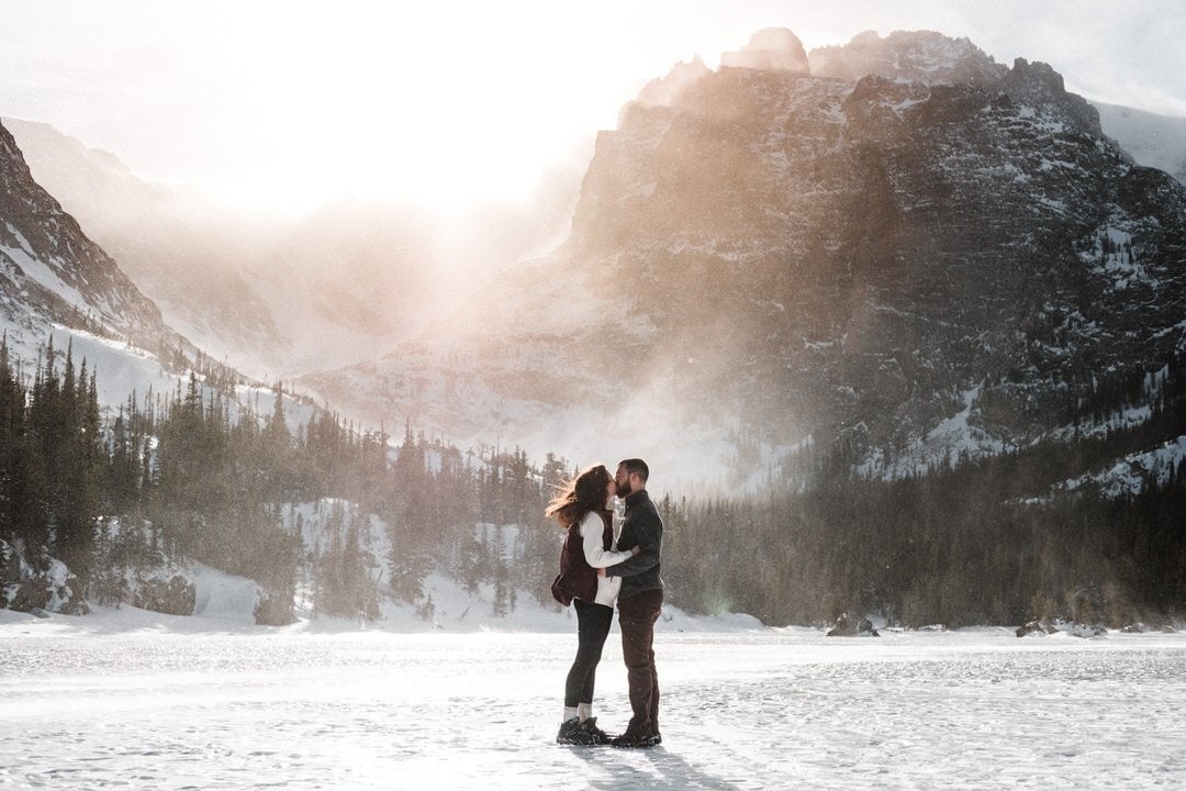 Frozen alpine lake engagement session blizzard at sunset in Rocky Mountain National Park