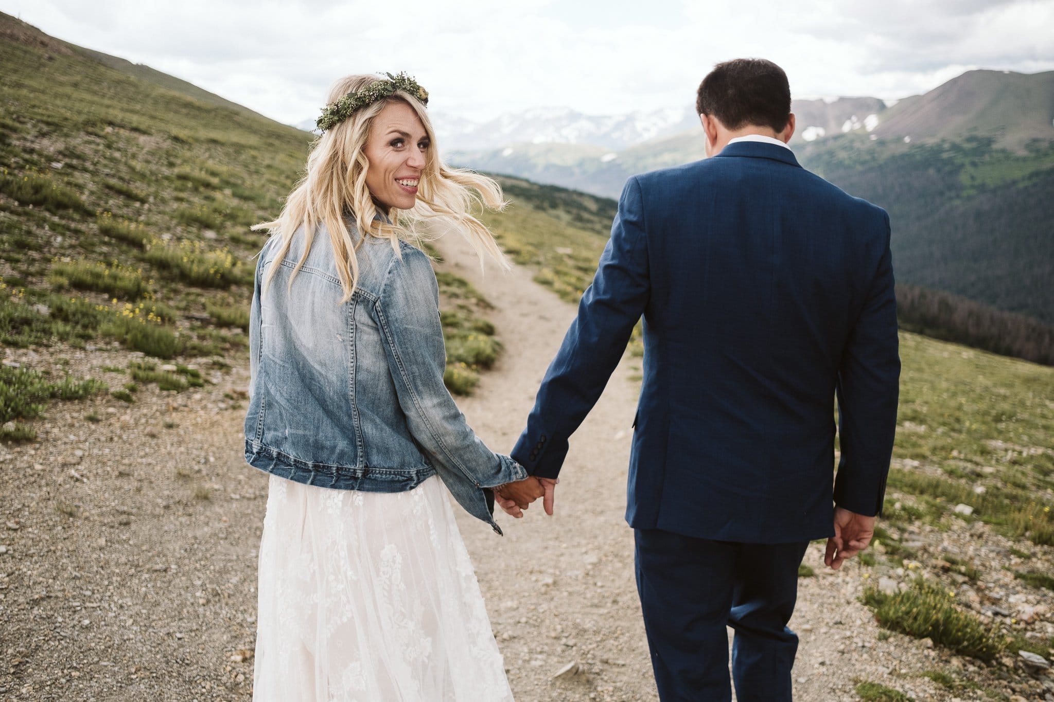 Bride and groom hiking elopement photos at Trail Ridge Road, Rocky Mountain National Park wedding, bride in denim jacket and wedding dress