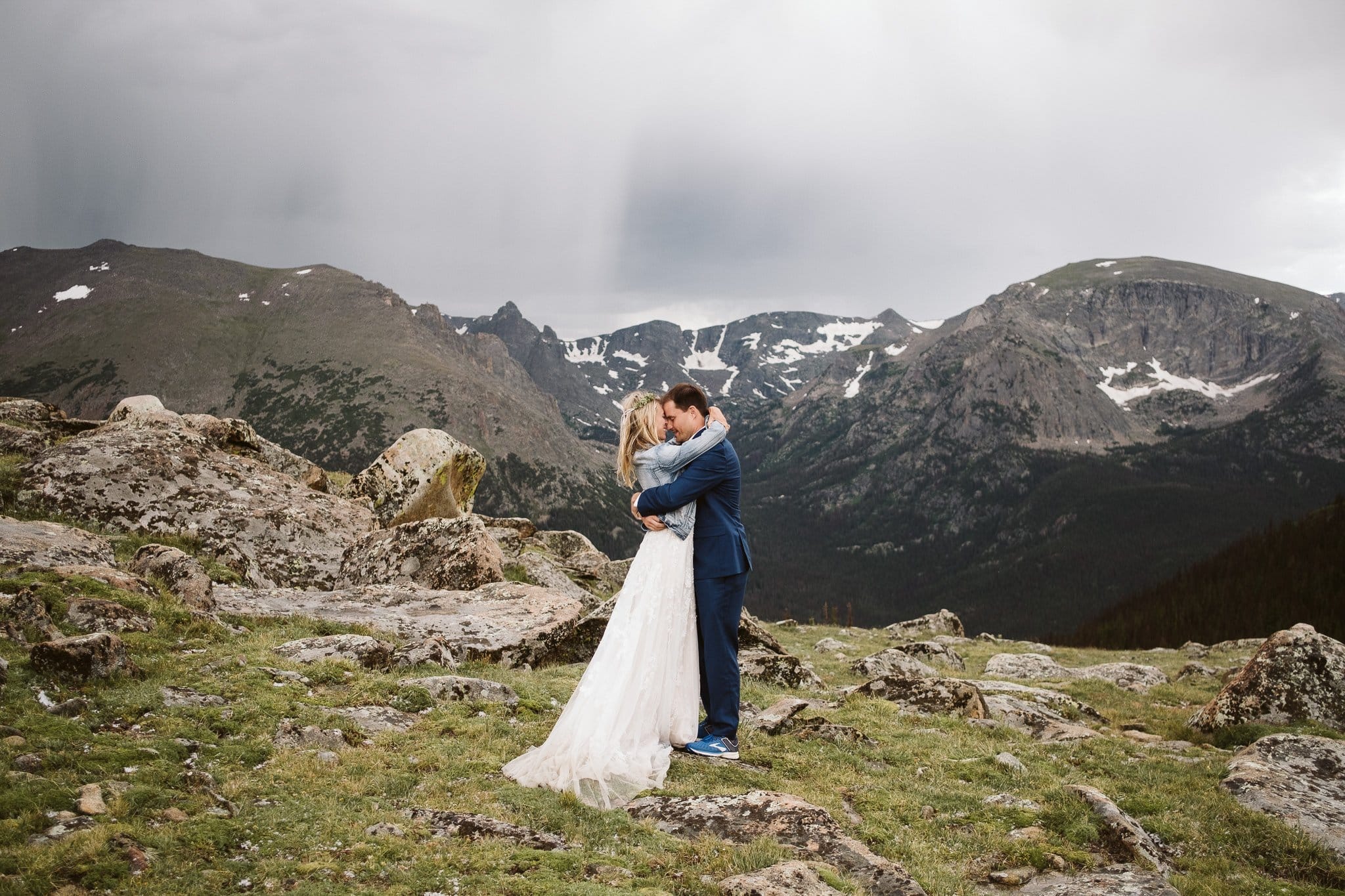 Bride and groom hiking elopement photos at Trail Ridge Road, Rocky Mountain National Park wedding, bride in denim jacket and wedding dress, Colorado elopement photographer