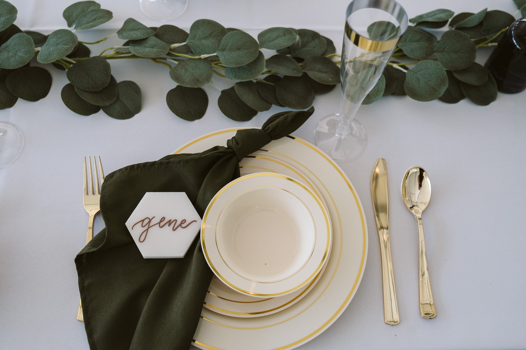 Wedding reception decor with dark green napkins and hexagonal shaped marble with gold calligraphy