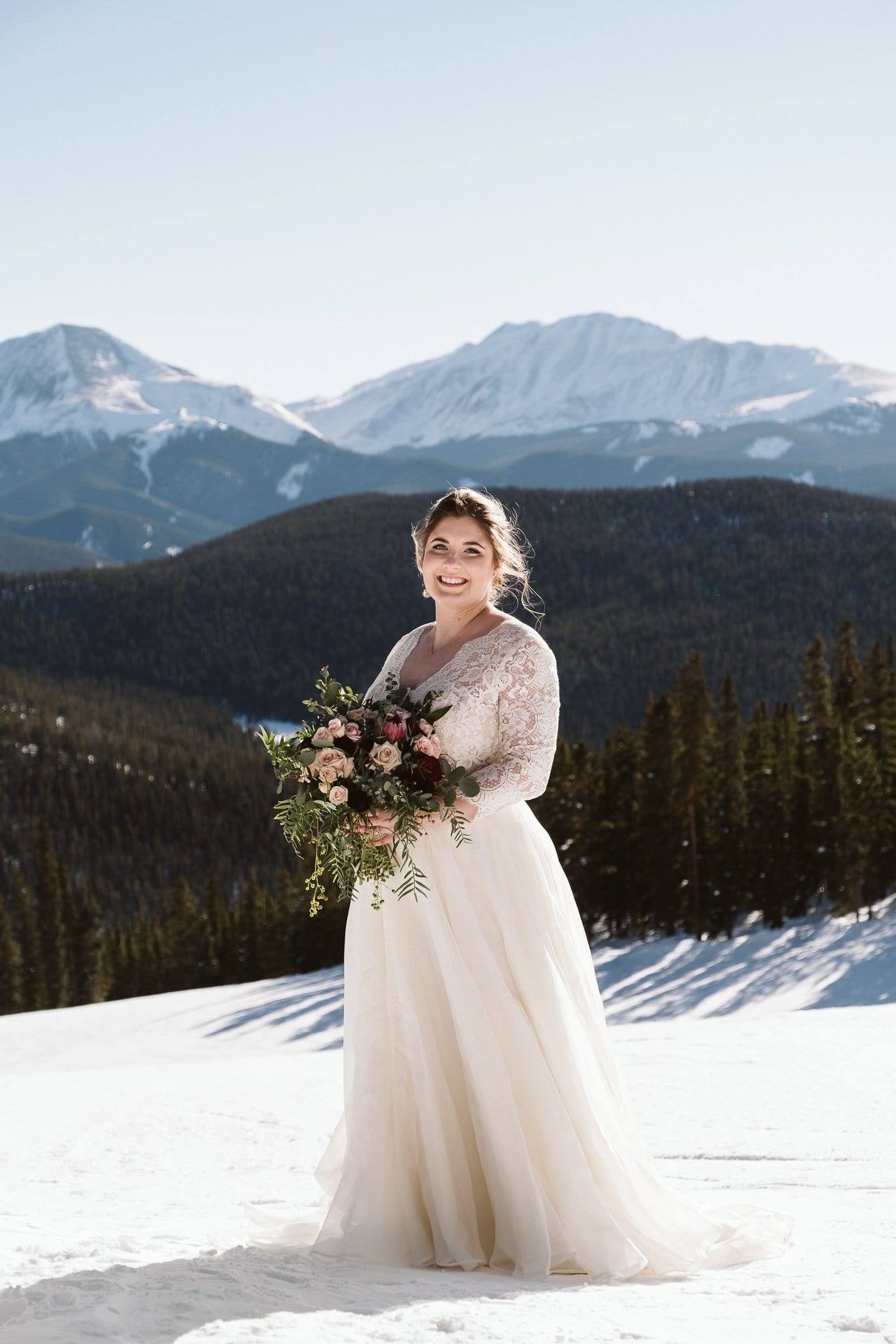 Bride wearing off-white long sleeve wedding dress at winter elopement in the snow.