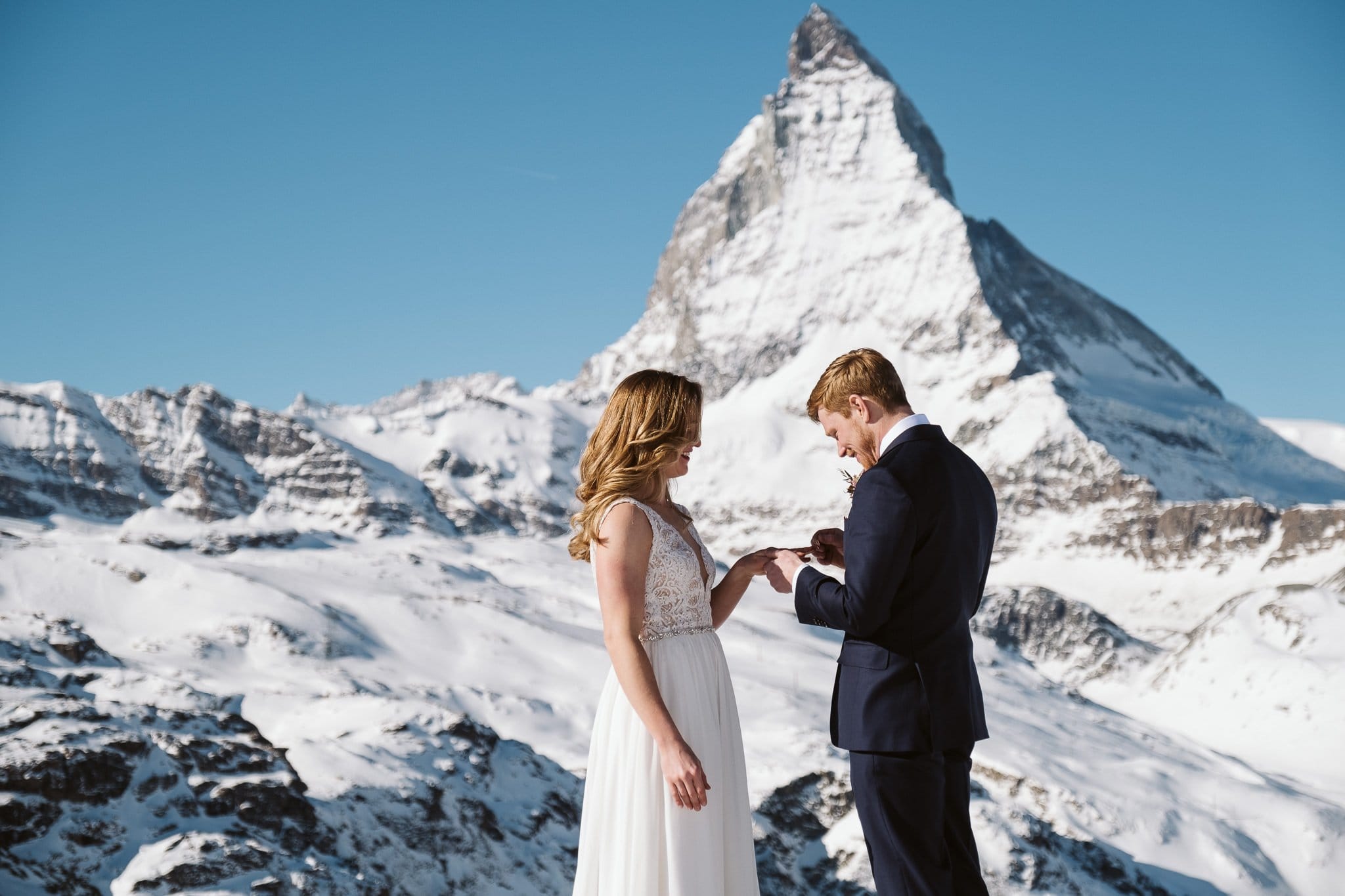 Bride and groom exchange wedding rings in front of Matterhorn in Zermatt. Switzerland elopement photographer.