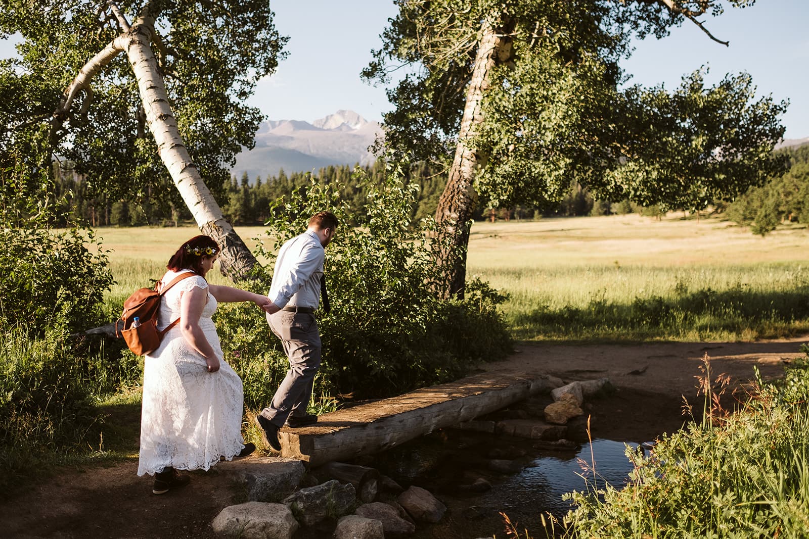 Bride and groom walk over creek at Upper Beaver Meadows