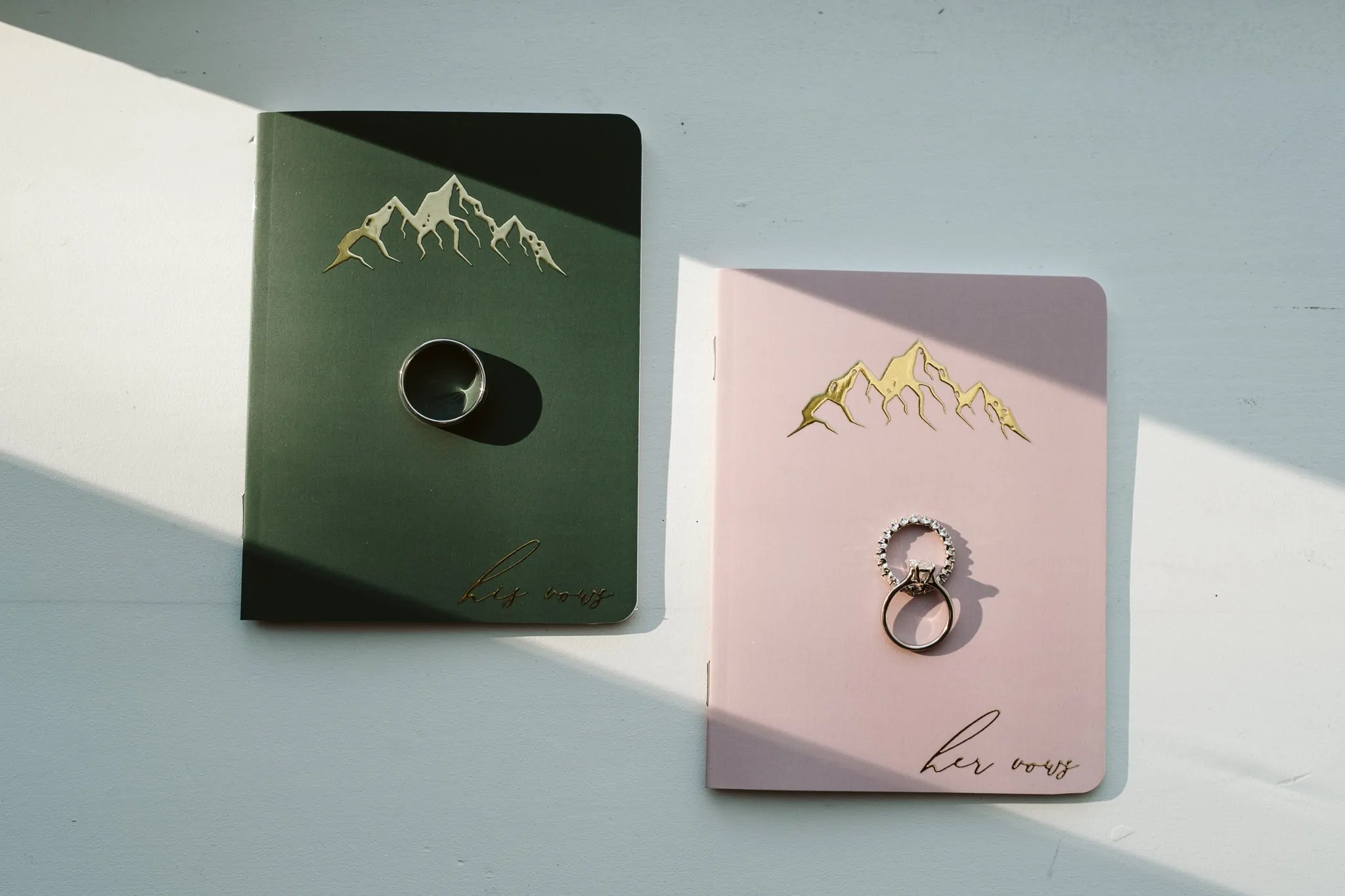 Green and pink vow books with mountains