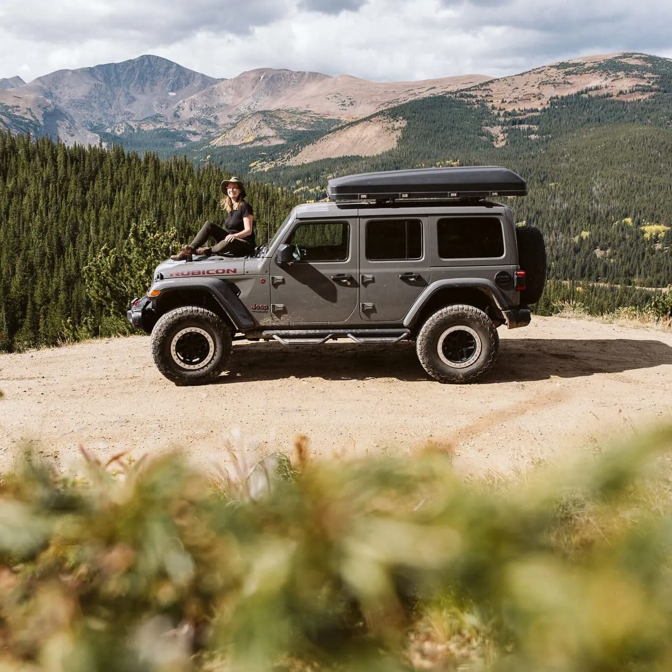 Nina Larsen Reed, sitting on the hood of a Jeep in the Colorado mountains