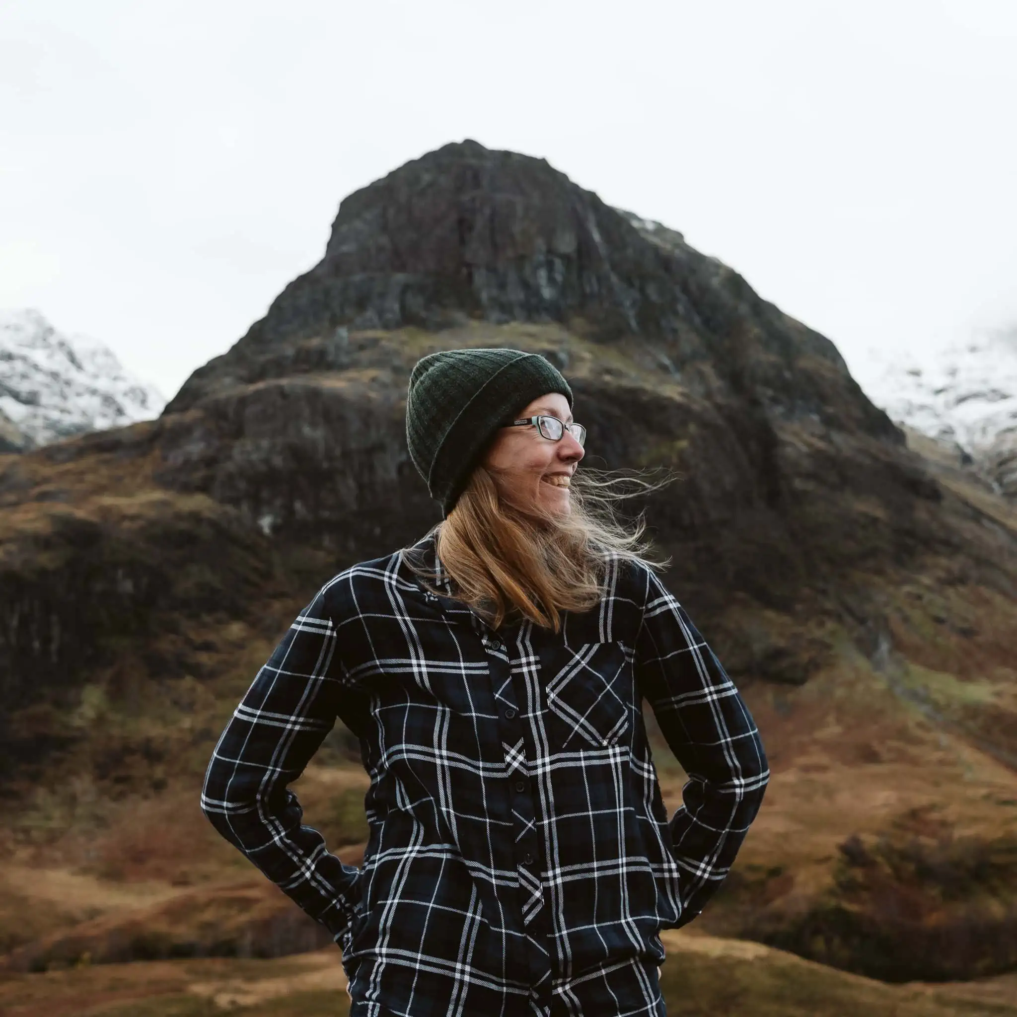 Nina Larsen Reed, an LGBTQ+ elopement photographer, standing in front of a mountain